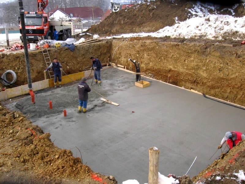 Concrete being poured and worked while the surface is still plastic