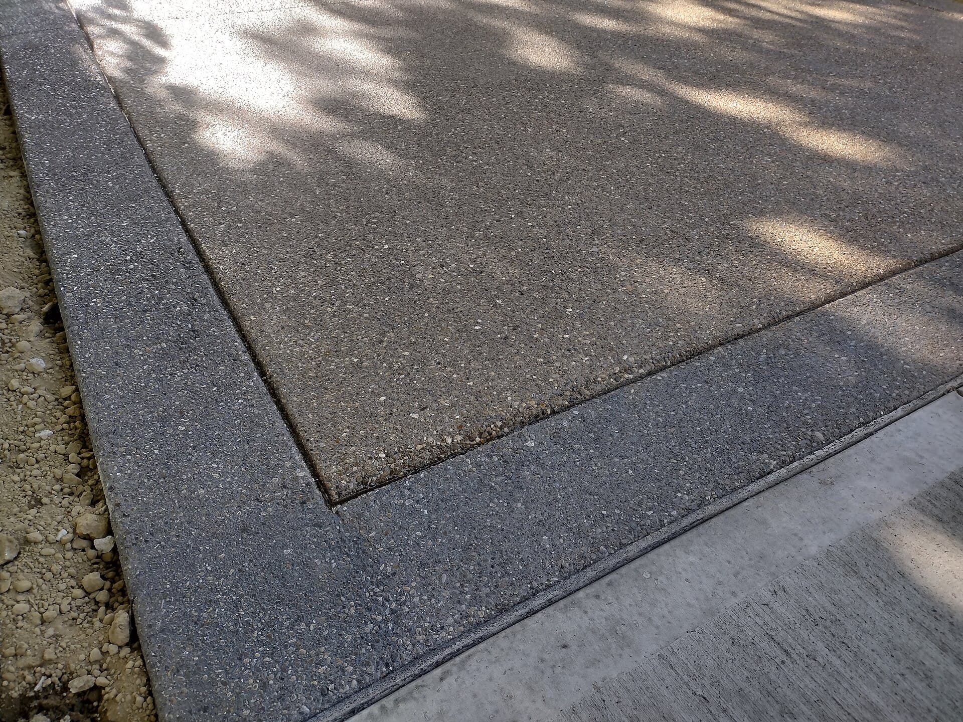 Close-up of exposed aggregate concrete with contrasting sealed borders