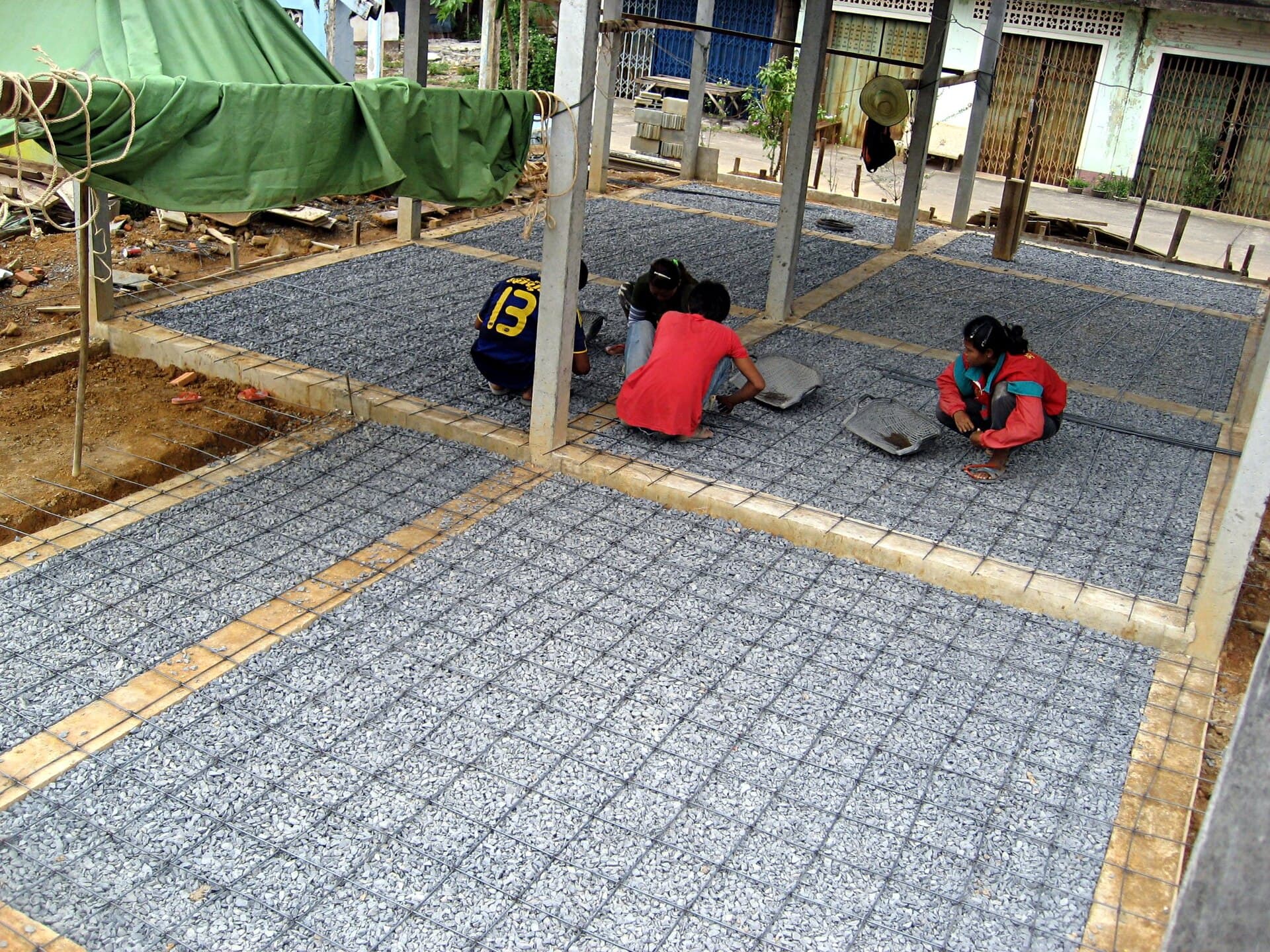 Workers tying reinforcement mesh for a concrete floor slab